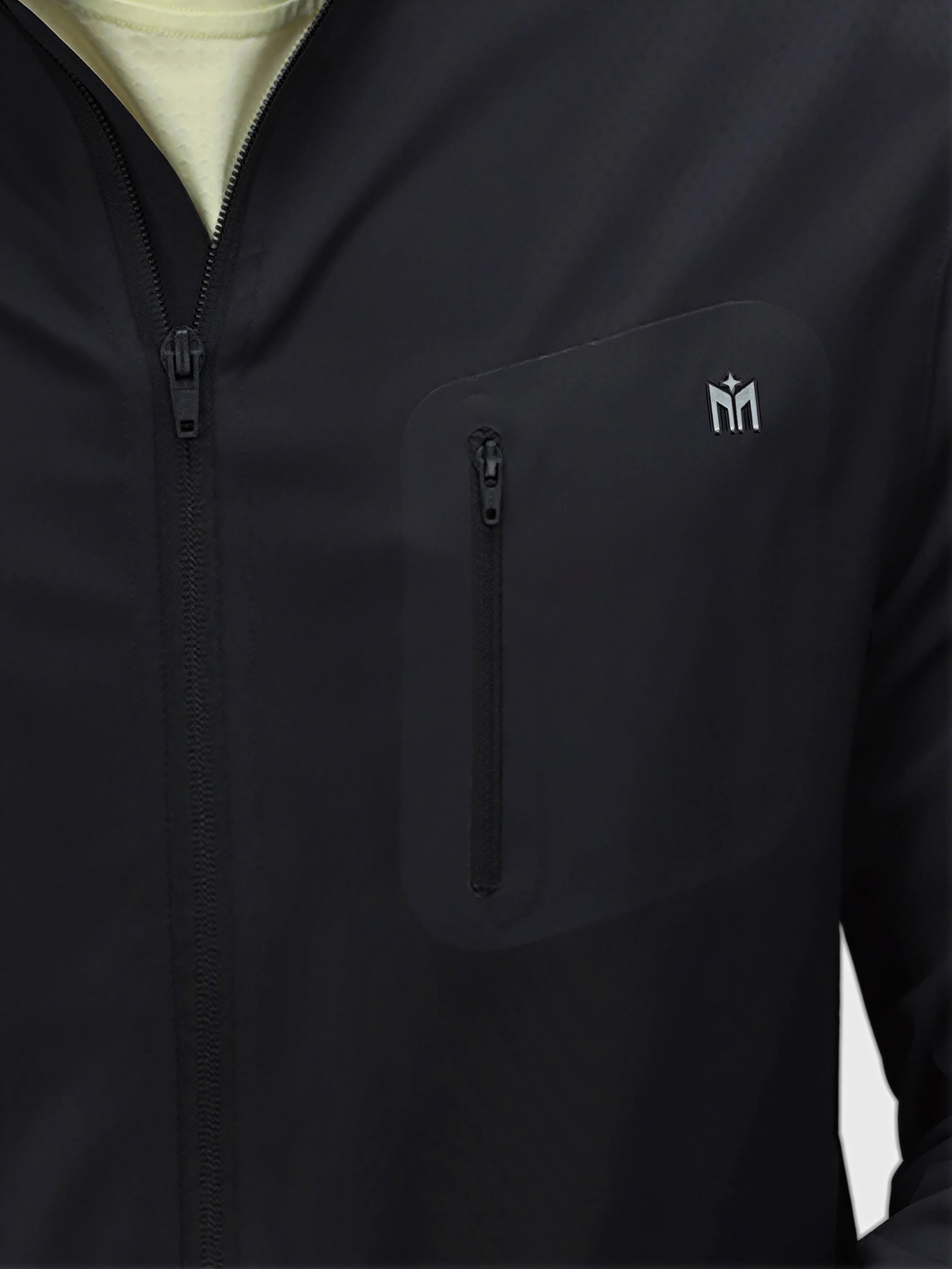 Close-up of black Echelon Jacket by MUEV featuring zippered chest pocket in padel and pickleball apparel