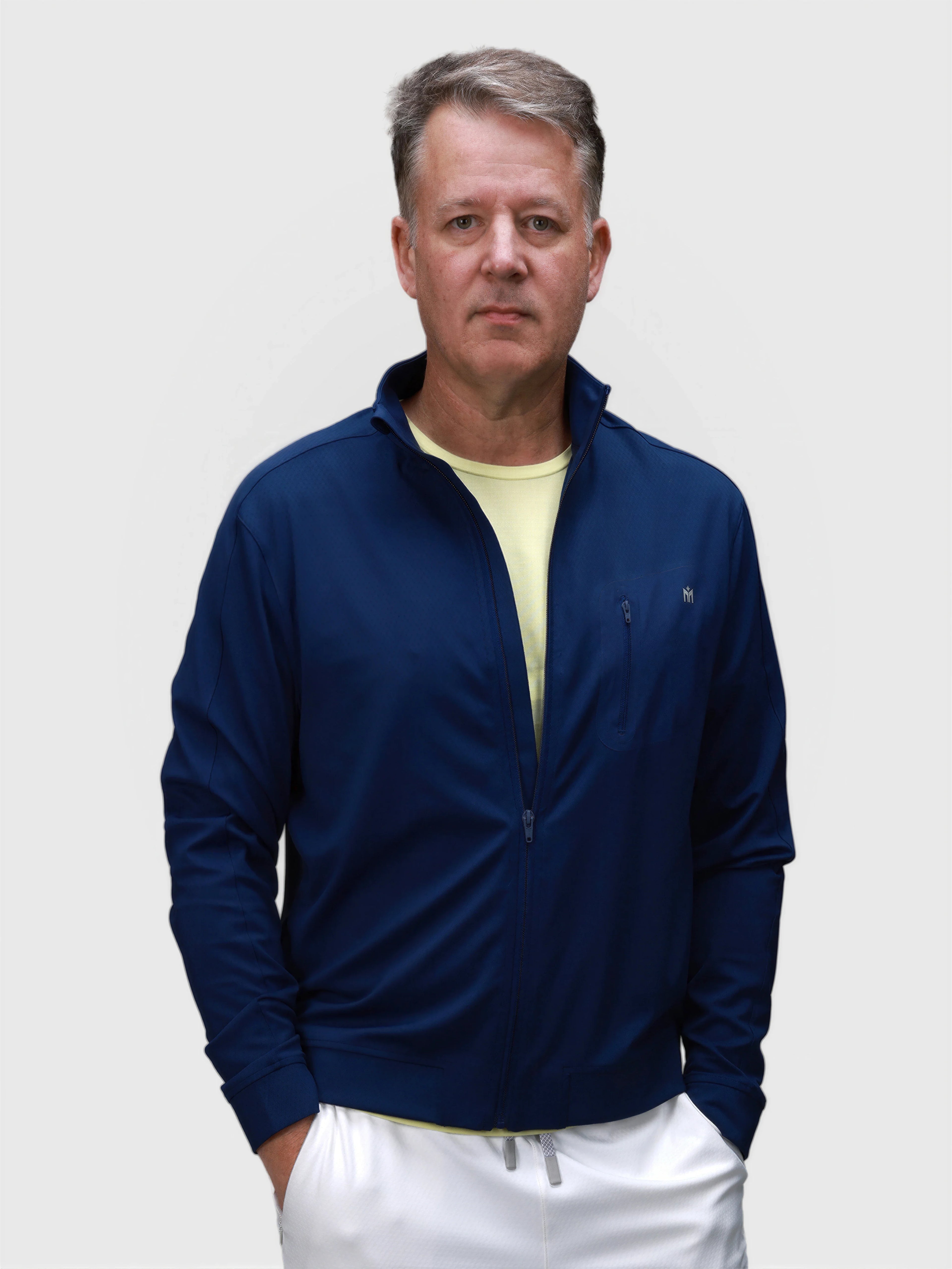 Man wearing Medieval Blue Echelon Jacket with zippered chest pocket in pickleball apparel by MUEV