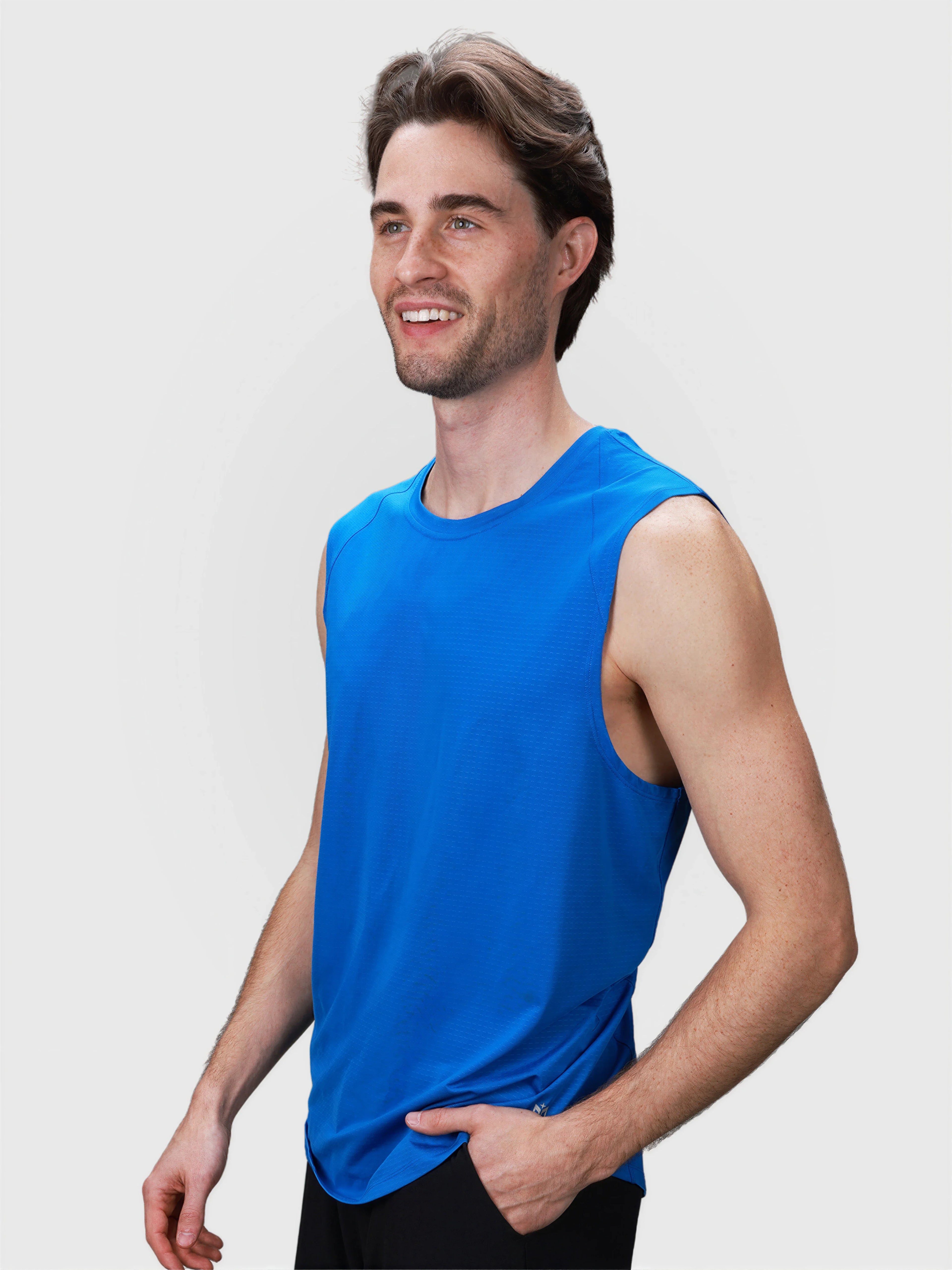 Man wearing bright blue sleeveless tank top in pickleball clothing by MUEV shown smiling and posed at slight angle